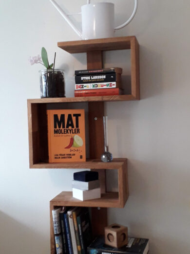 Vägghylla i massiv ek (limfog) som slingrar sig uppifrån och ner med 5 hyllplan i olika bredd.