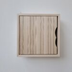 Litet skåp i massiv björk med lasergraverat mönster på dörren.