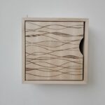 Litet skåp i massiv björk med lasergraverat mönster på dörren.